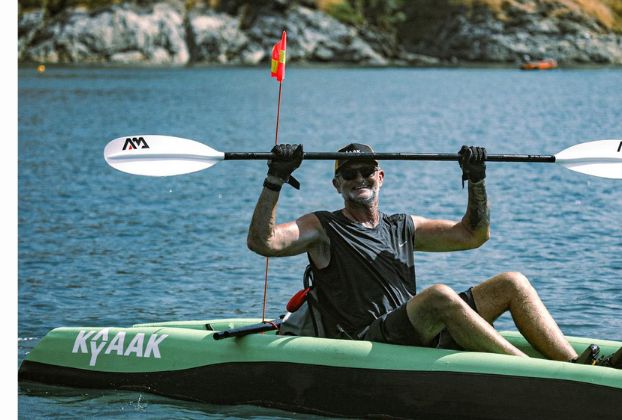 Paddler raising his paddle on a green KYYAAK